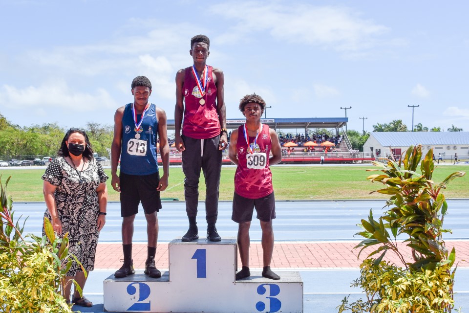 U16 Boy's Champion Andrew Stone (c) receives his medal from Senior School Inspector Mrs. Tammy Hopkins (l) after winning the boys' U16 long jump  competition at the recent Inter-Secondary School Sports Meet. Also in the photo are Rudolph Powell (standing in for 2nd place winner  Ishmael Jones) and  Myron Cruz, who placed third.